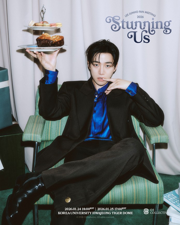 A young man sitting in a green striped chair, wearing a black blazer and blue shirt, holds a tiered plate with macarons and a muffin. He has a stylish hairstyle and poses with a finger on his lips, set against a backdrop of curtains.