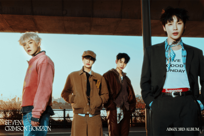 Four members of a music group posing outdoors against a city backdrop, each wearing stylish and trendy outfits with varying colors and accessories.