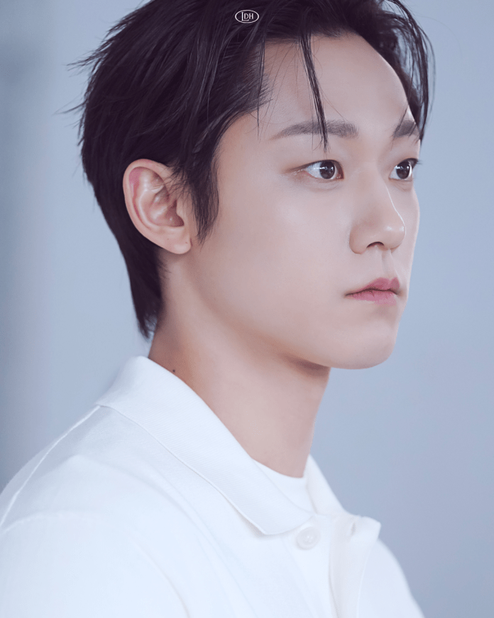 Profile portrait of Lee Do hyun with short dark hair, wearing a white collared shirt, set against a soft blue background.