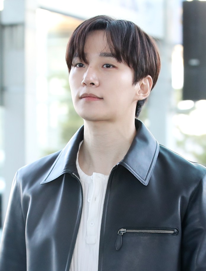 Lee Junho with short dark hair wearing a black leather jacket and a white shirt, looking slightly away from the camera.