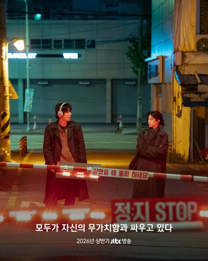 A scene at night featuring Go Youn- jung and Koo kyo-hwan standing near a barrier with a 'STOP' sign, illuminated by streetlights, conveying a sense of tension.