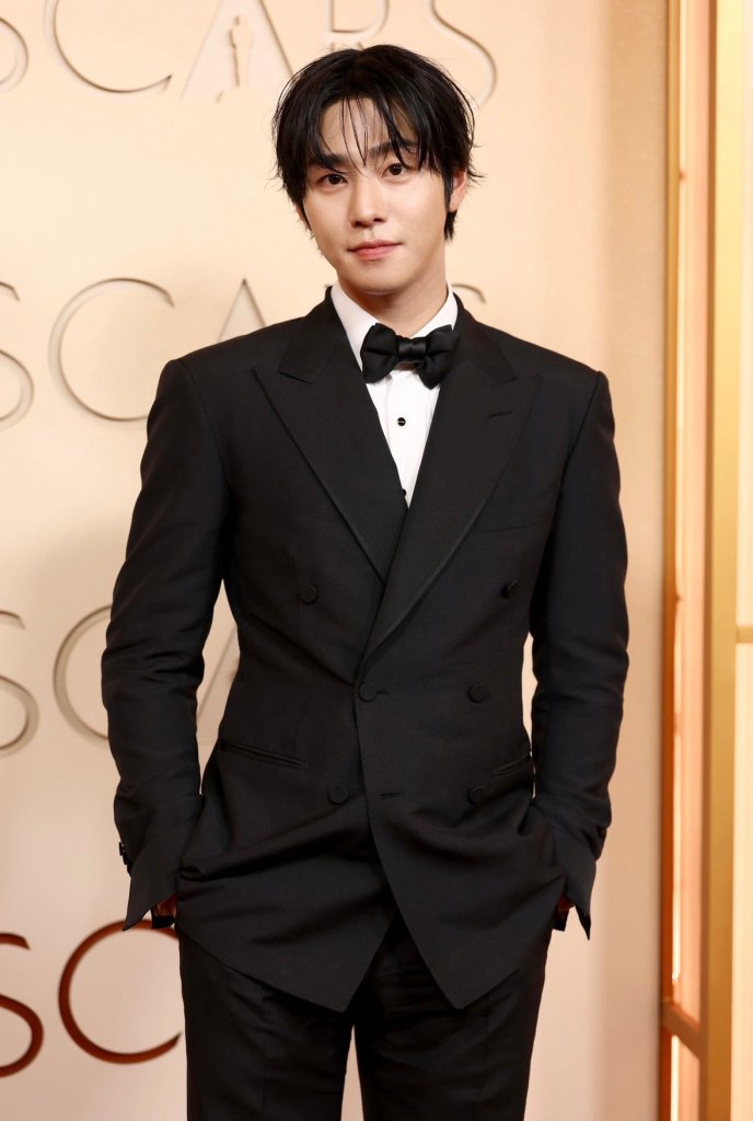 Ahn Hyo Seop in a black tuxedo with a bow tie, posing confidently in front of an elegant background featuring the word 'OSCARS'.