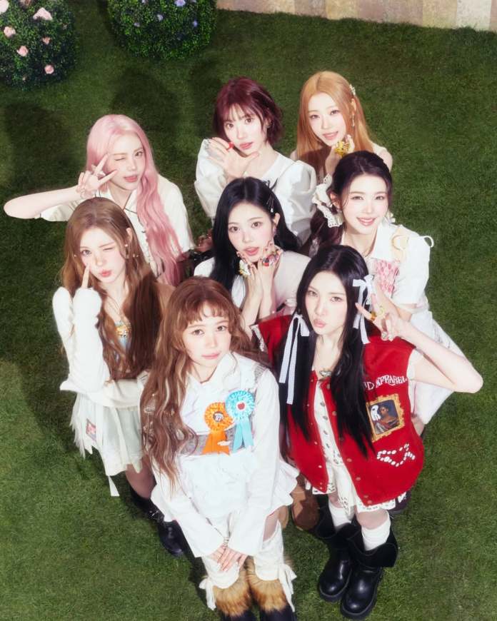 Hearts2Hearts posing together in a garden setting, all wearing stylish outfits and smiling at the camera. Some are making playful hand gestures.