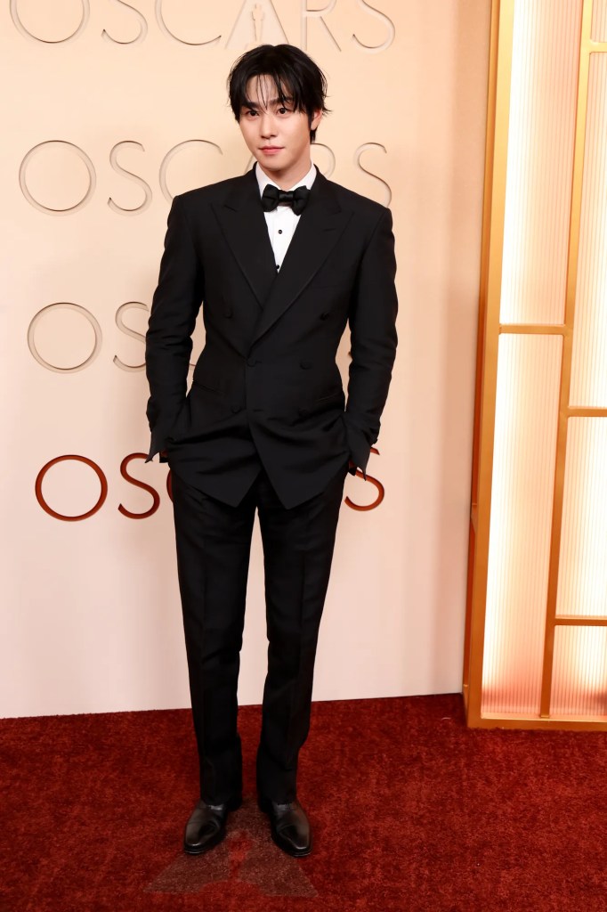 Ahn Hyo Seop in a black tuxedo with a bow tie, standing confidently on a red carpet at an awards event, with an 'Oscars' backdrop.