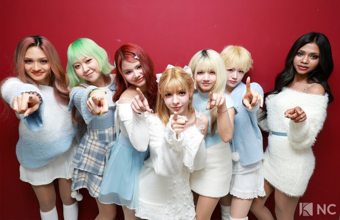 MepC posing together in front of a red background, all pointing towards the camera, wearing colorful outfits with various hair colors.