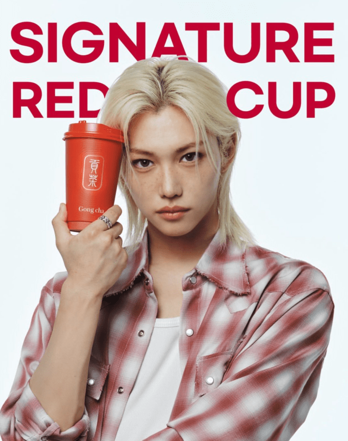 A person with long blonde hair holds a red cup labeled 'Gong cha' while wearing a plaid shirt against a white background with the text 'SIGNATURE RED CUP' in bold red letters.