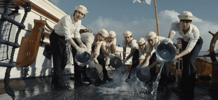 BTS in white uniforms and hats, working together to pour water from metal bowls over the side of a ship deck.