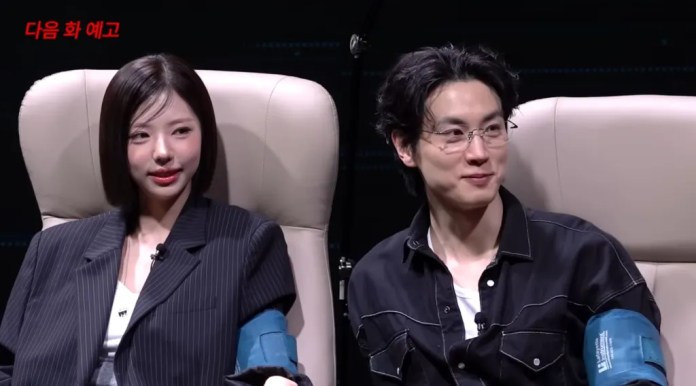 Kim Go eun and Jo Igeon sitting in chairs, engaged in conversation during a studio interview. The woman is wearing a pinstripe blazer and has medium-length hair, while the man is wearing a black shirt and glasses.