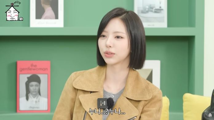 Kim Go Eun wearing a beige jacket sits in a brightly colored room, engaging in conversation. Behind her are several books and decorative items on shelves.