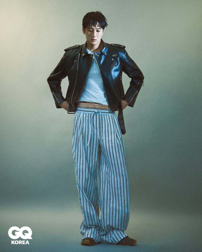 Ahn Bo-hyun wearing a leather jacket and striped pants, posing with a focused expression against a softly lit background.