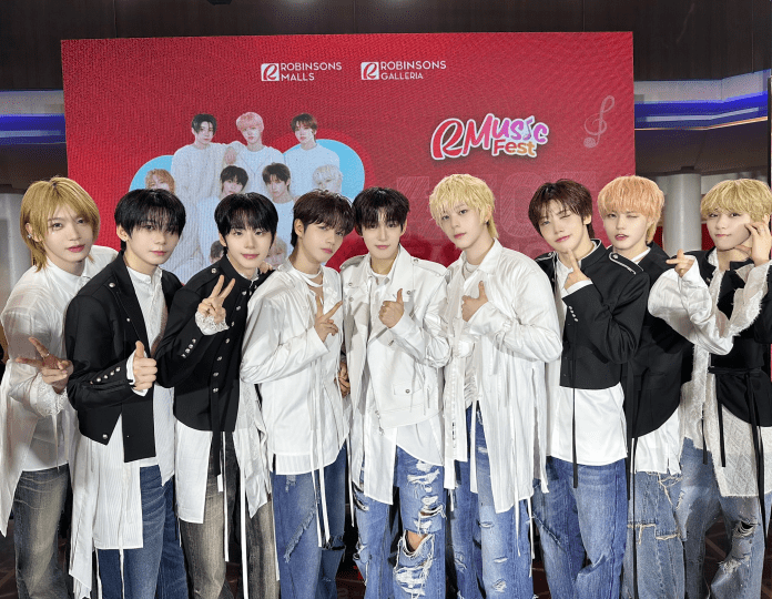 AHOF posing together at an event, wearing stylish outfits, against a backdrop featuring promotional branding for RMuscle Fest and Robinsons Malls.