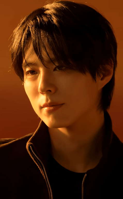 A close-up portrait of Park Bo-gum with dark hair and a slight smile, set against a warm orange background.