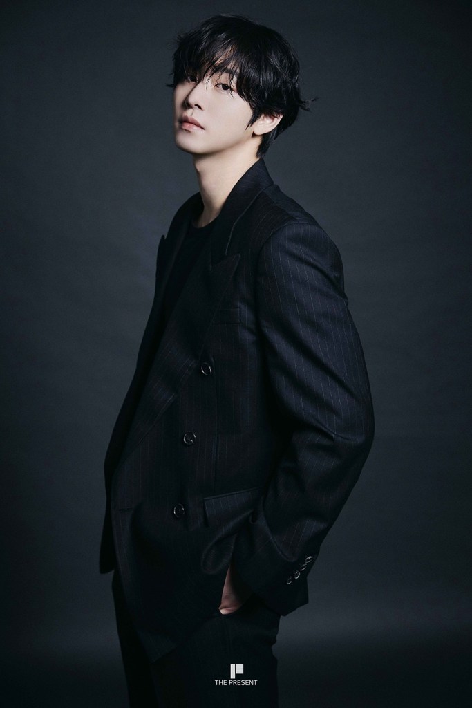 A side profile of Ahn Hyo-seop wearing a stylish black pinstripe suit, with a casual black shirt underneath, standing against a dark background.