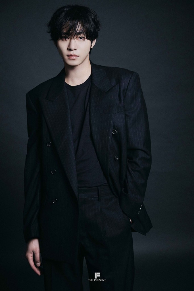 Ahn Hyo-seop with stylish, tousled hair wearing a black pinstripe suit and a fitted black shirt, posed against a dark background.