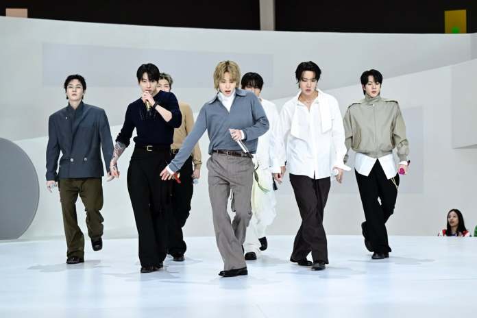 BTS walking confidently on a fashion runway, dressed in various modern outfits.