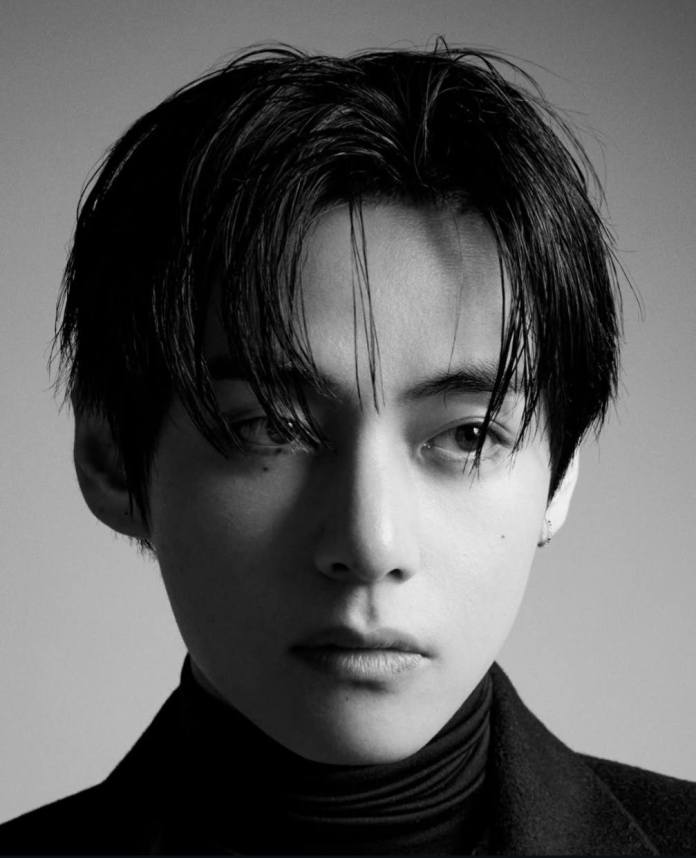 V with dark, styled hair and a turtleneck, looking thoughtfully to the side.