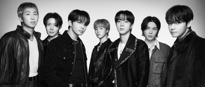 A black and white portrait of the BTS members standing together, showcasing a variety of stylish outfits and hairstyles.