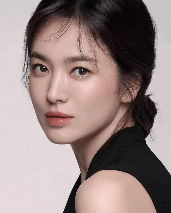 A close-up portrait of Song Hye-Kyo with long dark hair, wearing a black sleeveless top, looking directly at the camera with a soft expression.