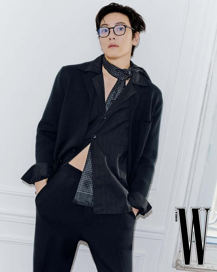 Ji Chang-wook in a stylish black outfit with glasses, posing confidently against a white wall.