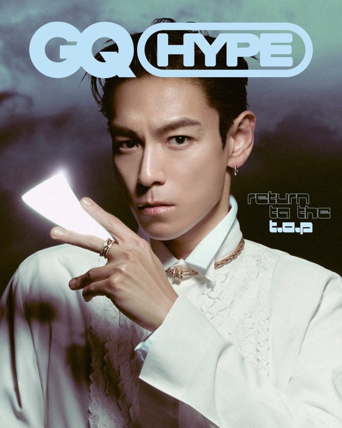 T.O.P poses for the cover of GQ HYPE, wearing a white, intricately designed outfit, with a soft focus background and dramatic lighting. He holds a light source while making a peace sign with his hand.