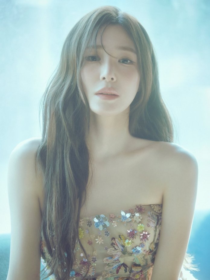 A close-up portrait of Tiffany Young with long, wavy hair wearing a strapless floral dress, looking directly at the camera with a soft expression.