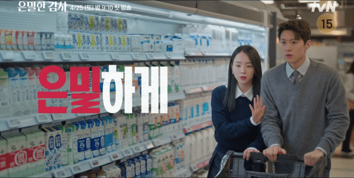 Shin Hye Sun in a dark sweater and Gong Myung in a light sweater are shopping in a supermarket aisle filled with dairy products. Shin Hye Sun is gesturing towards something while Gong Myung looks concerned.