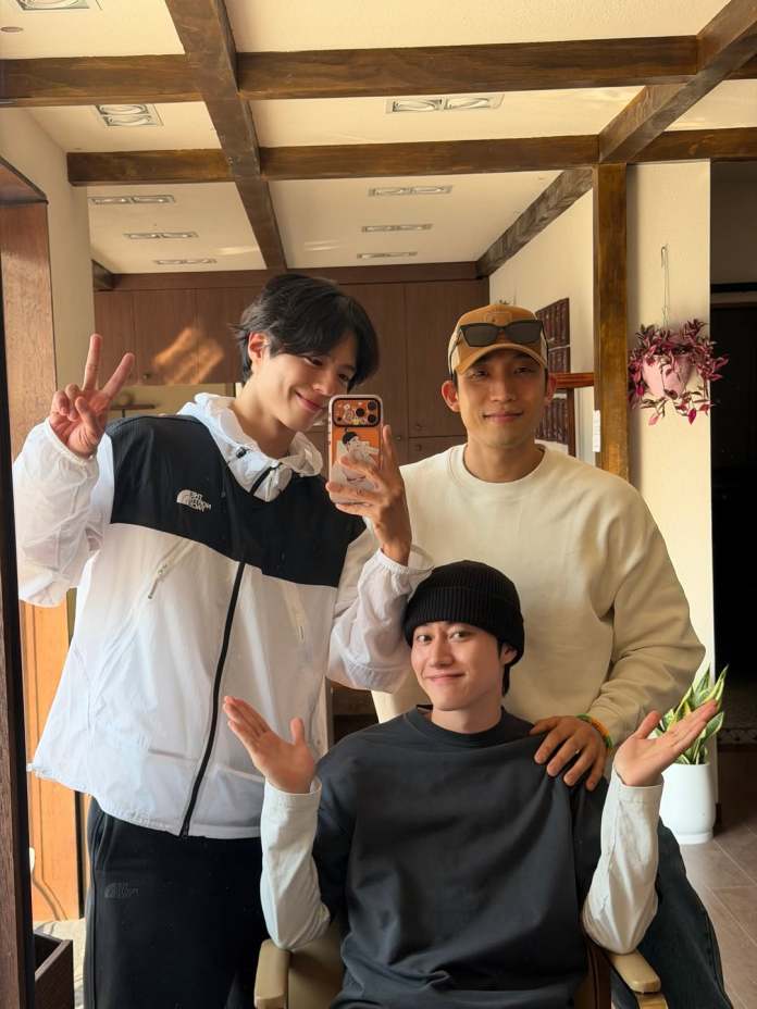 Park Bo-gum, Lee Sang-yi, and Kwak Dong-yeon posing for a selfie in a cozy indoor setting, with Park Bo-gum making a peace sign, Kwak Dong-yeon in a beanie, and Lee Sang-yi smiling while seated.