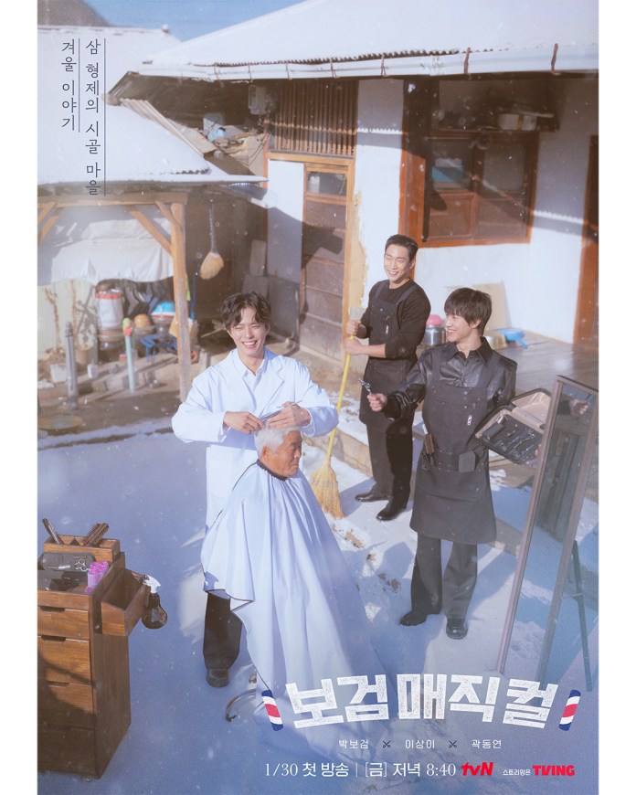 A festive winter scene featuring a barbershop setting. An older man is getting a haircut outside while Park Bo-gum styles his hair. Lee Sang-yi, and Kwak Dong-yeon are observing and smiling nearby, surrounded by snowy surroundings and traditional buildings.