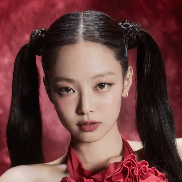 Jennie with long, sleek hair styled in two high pigtails, wearing a red ruffled top against a blurred red background.