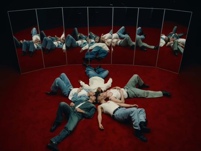SANTOS BRAVOS members lying in a circular formation on a red carpet, surrounded by mirrors reflecting their poses.
