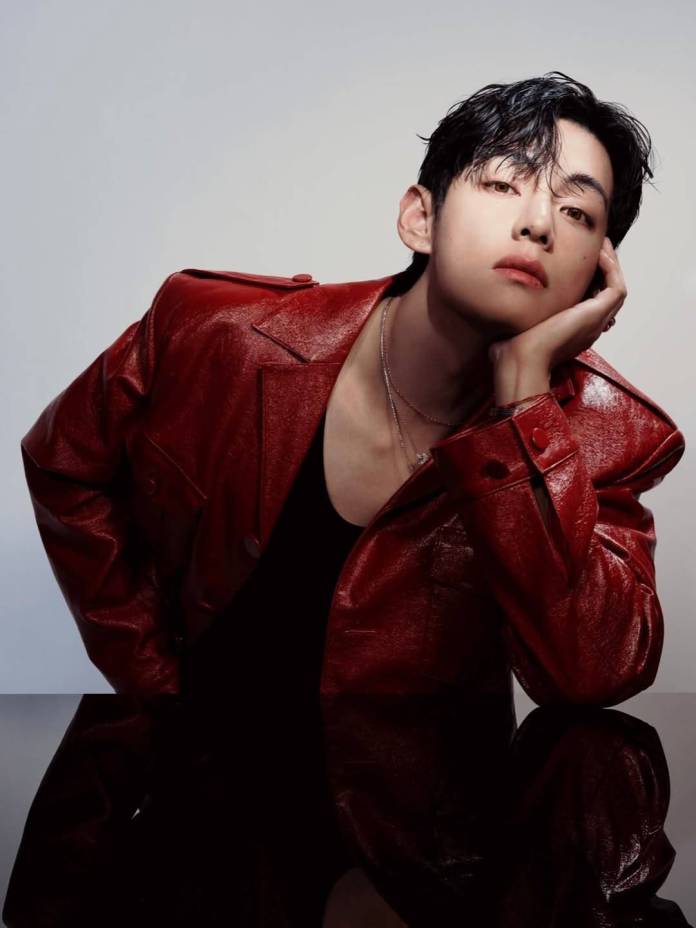 A person resting their head on their hand, wearing a shiny red leather jacket, against a neutral background.