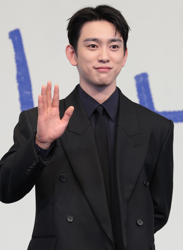 Park Jin-young in a black suit waving and smiling at an event.