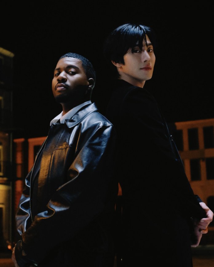 Ahn Hyo-seop and Khalid standing back to back in a dimly lit urban setting, Khalid wearing a black leather jacket and Ahn Hyo-seop in a black coat.
