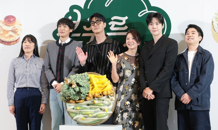 Bonjour Bakery cast  poses together in front of a decorative dessert display at an event.