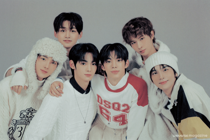 TWS posing together for a photoshoot, wearing stylish winter clothing and accessories, with a soft gray background.