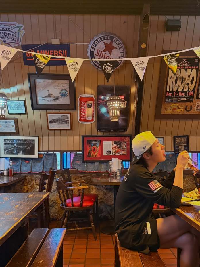 V enjoying a meal in a cozy restaurant adorned with various decorations and banners on the walls.