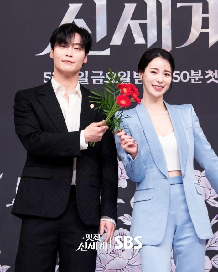 Lim Ji-yeon and Heo Nam-jun posing together at a promotional event, one holding a bouquet of flowers, with a decorative floral background.