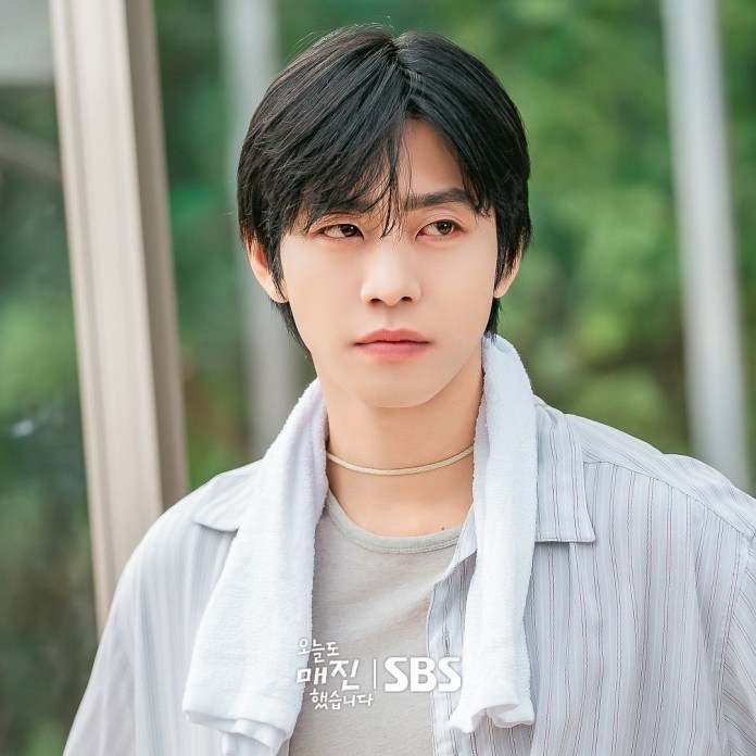 Ahn Hyo-seop with black hair wearing a casual striped shirt, looking thoughtfully into the distance, with a towel draped around his neck.