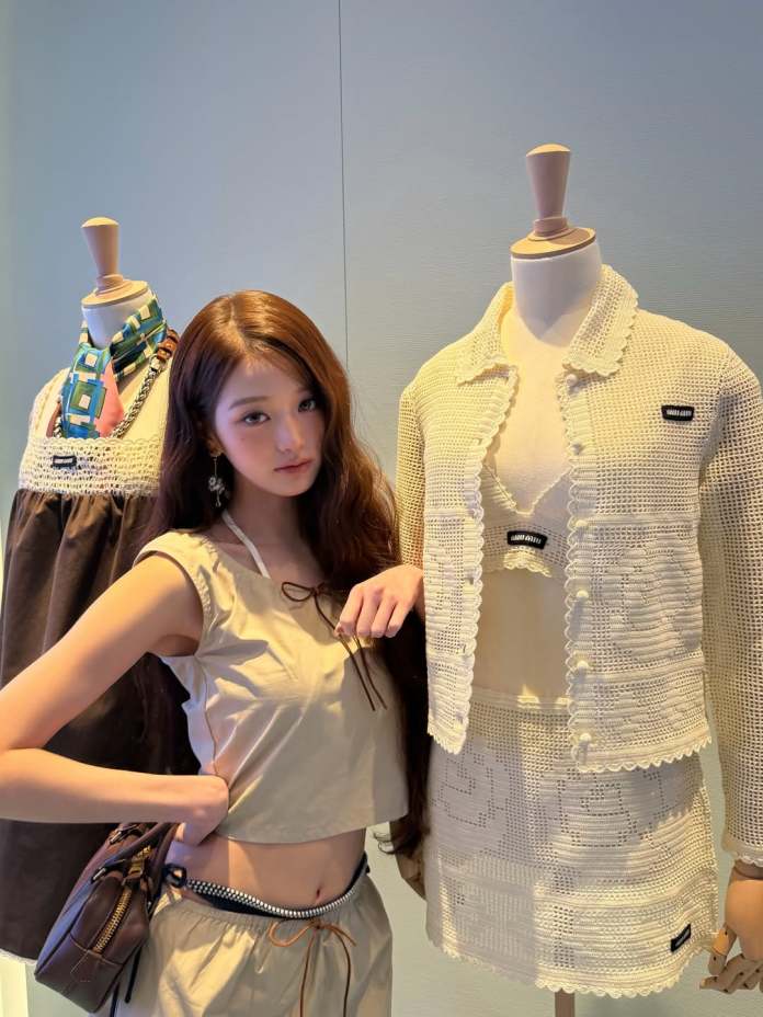 Jang Wonyoung posing next to two mannequin displays wearing stylish outfits, featuring a crochet jacket and a patterned top.