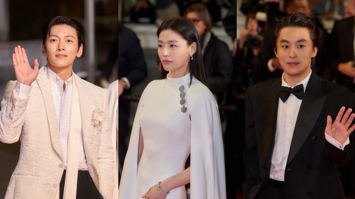 Ji Chang-Wook, Jun Ji-hyun and Koo Kyo-hwan on a red carpet event, each waving. Ji Chang-Wook wears a stylish white suit,  Jun Ji-hyun is in an elegant white dress with a cape, and Koo Kyo-hwan is dressed in a classic black tuxedo.