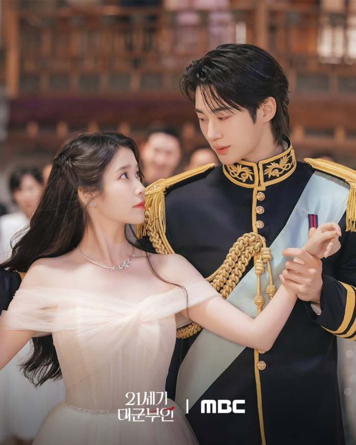 A romantic scene featuring Byeon Woo-seok in a formal military uniform and IU in a light, off-shoulder dress, both gazing into each other's eyes as they dance together.