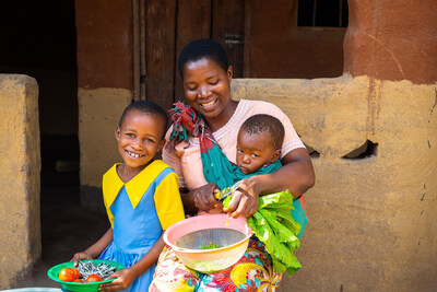 Happiness, 5 years old, sitting with her mother, Mary Diston aged 30, who is carrying 1-year-old, Laphael while chopping vegetables outside house in Mukwala Village, TA Mkhumba, Phalombe District, Southern Malawi. Mary Diston, aged 30, who is one of the care group members in Mukwala village, says she learnt how to prepare food from the groups and this has benefited her family since their meals are well balanced with all six nutrition food groups. © UNICEF/UNI591049/Mmina/Elephant Media