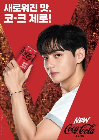 V holding a can of Coca-Cola Zero in a promotional advertisement with a vibrant red background.