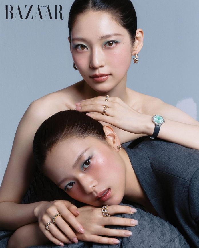 Gong Seung-yeon and TWICE member Jeongyeon pose elegantly against a plain background, showcasing jewelry and fashion. One model is seated with her head tilted slightly, while the other leans in with her arms crossed, highlighting their striking makeup and accessories.