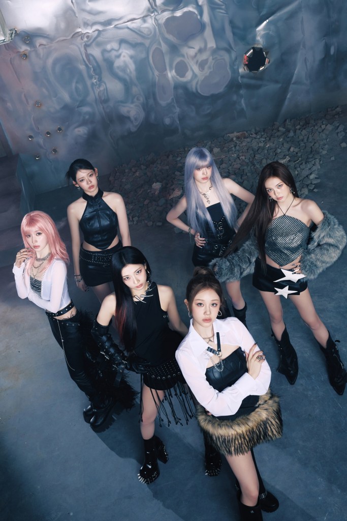 BABYMONSTER posing in stylish, edgy outfits, featuring a mix of leather and metallic textures, in a modern, industrial setting.