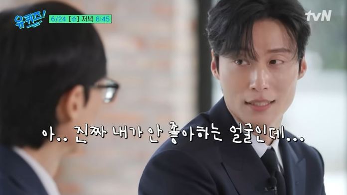 Heo Nam-jun in a suit appears to be in conversation, looking at another person off-camera with a focused expression.
