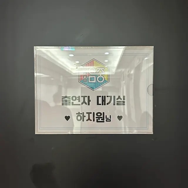 A sign displayed on a wall indicating a waiting room or area for performers, featuring the Korean words '출연자 대기실' (Performer Waiting Room) and a name '하지원'.