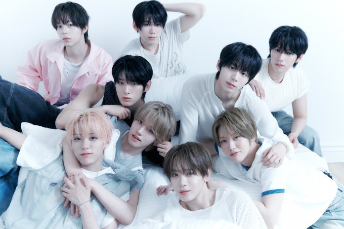 AHOF posing together on a bed, dressed in light-colored, casual clothing, with a soft, neutral background.