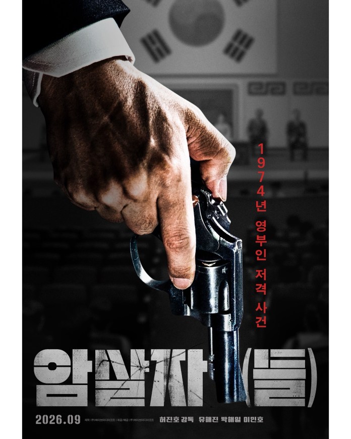 A close-up of a man's hand gripping a revolver, with a blurred background featuring a South Korean flag and an audience. The image is promoting a film titled 'Assassin', set in 1974, with release date September 2026.