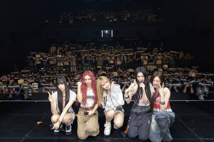 Keyveatz is posing on stage with fans holding banners in the background during a concert.